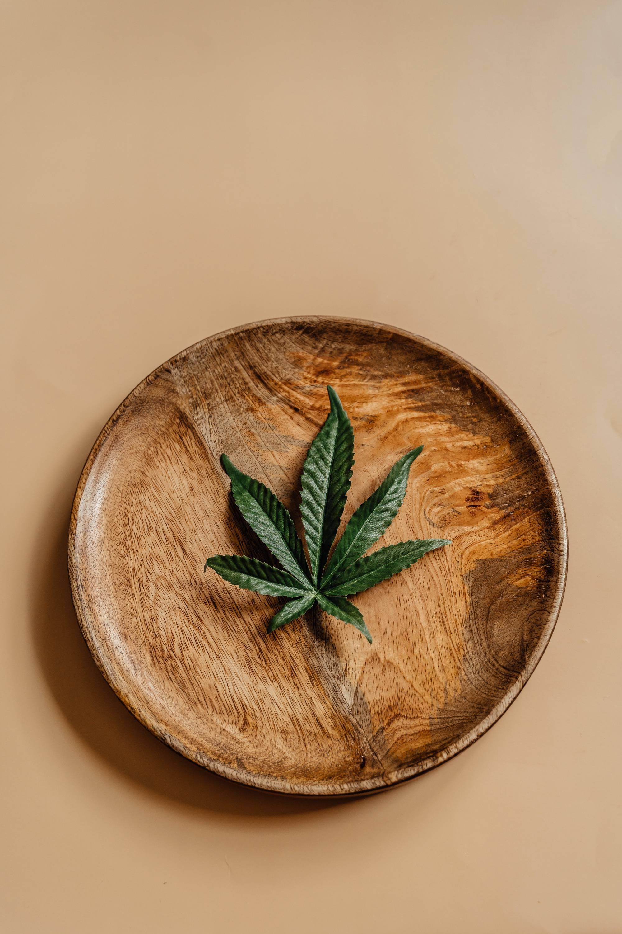 Cannabis leaf in a middle of a wooden plate